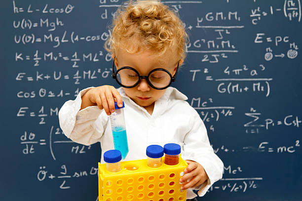 Young scientist with toy beakers Young scientist front a blackboard full of equations with test tubes albert einstein stock pictures, royalty-free photos & images
