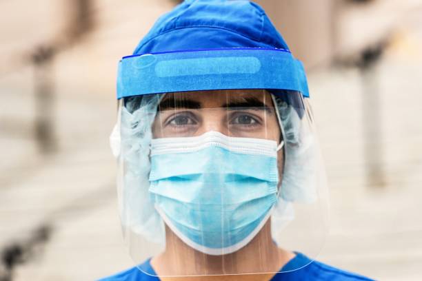 Young serious overworked, male young health care worker looking at the camera Young serious overworked, male young health care worker looking at the camera nurse face stock pictures, royalty-free photos & images