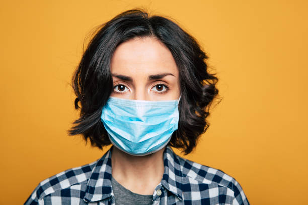 Young serious woman in a protective medical mask. Woman wearing face mask because of Air pollution or virus epidemic. obscured face stock pictures, royalty-free photos & images