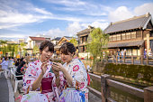 日本の伝統的な祭りでスマートフォンを使う浴衣の若い姉妹