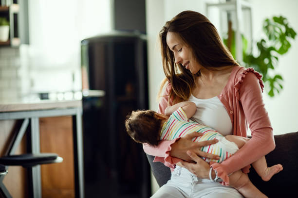 jonge lachende moeder borstvoeding haar baby thuis. - breastfeeding stockfoto's en -beelden
