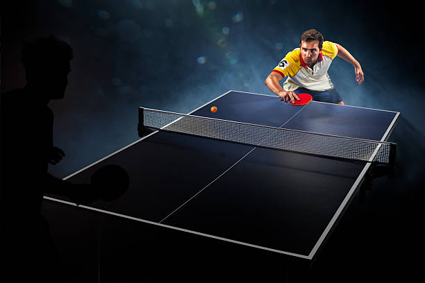 young sports man tennis player playing on black background with young sports man tennis player is playing on black background with lights table tennis stock pictures, royalty-free photos & images
