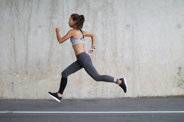 Young sports woman running outdoors stock photo