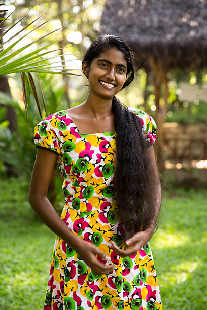 Young Sri Lanka girl in the garden Young, slim and beautiful Sri Lankan girl posing in the tropical garden of her house. She is in her 20s with dark skin and long hair.She is wearing a colorful dress. sri lanka women stock pictures, royalty-free photos & images