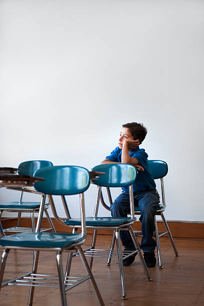 young student alone in a classroom stock photo