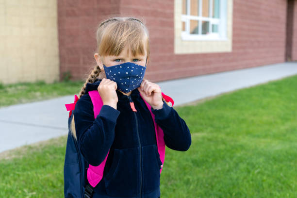 Young student caucasian girl wearing protective cotton mask for school. Return back to school, reopening, new life stock photo