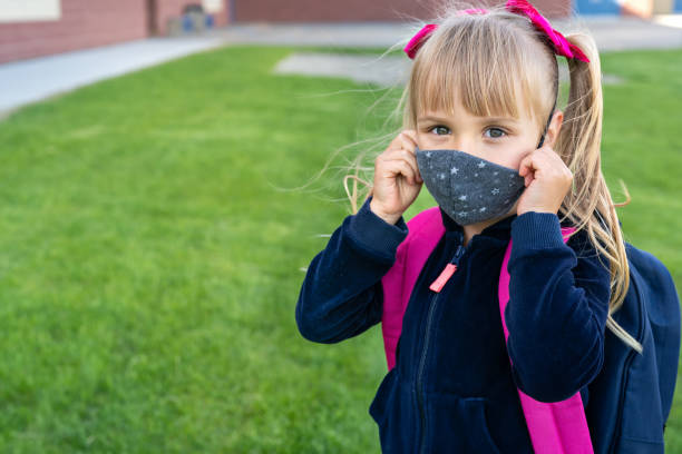 Young student caucasian girl wearing protective cotton mask for school. Return back to school, reopening, new life stock photo