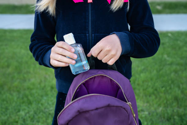 Young student girl holding hand sanitizer bottle reopening. Return back to school, new life concept stock photo