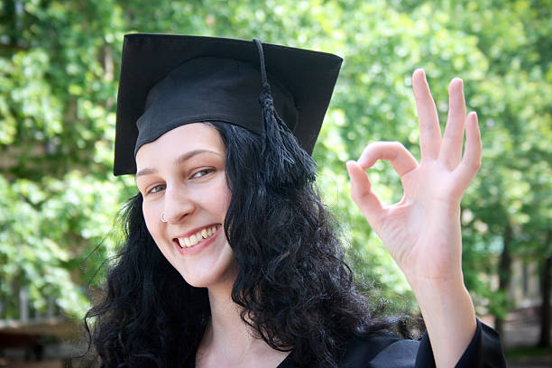 Young student in gown near the university with okay stock photo