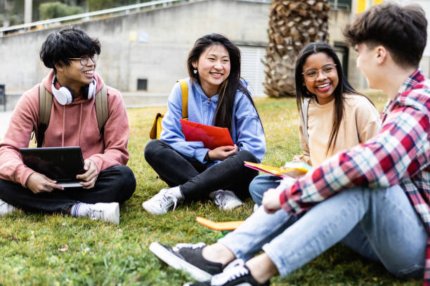 Young students sitting at the grass at campus university stock photo