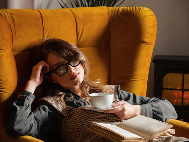 Young style woman with a cup of coffee and book sitting in armchair stock photo