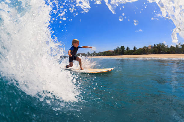 Young surfer learn to ride on surfboard on sea waves stock photo