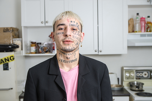 Young tattooed man posing in his kitchen