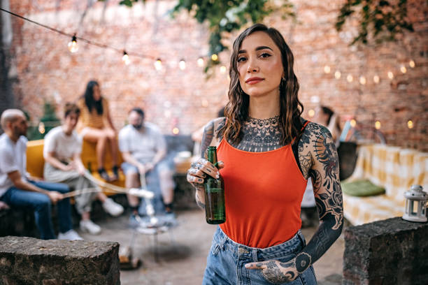 Young tattooed woman with bottle beer on garden party Photo of young tattooed woman with bottle beer on garden party tattooed stock pictures, royalty-free photos & images
