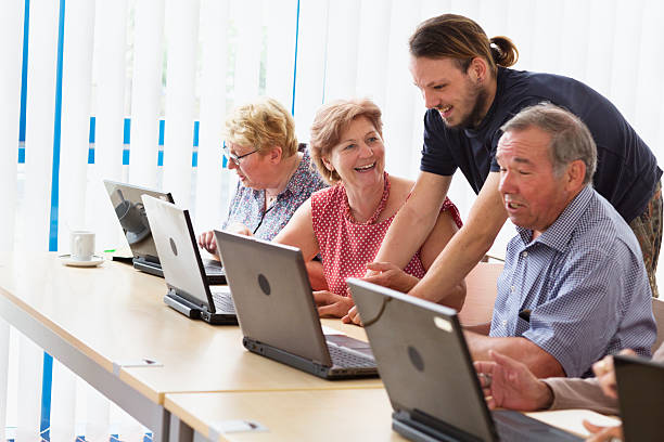 young teacher and senior adults learning in computer lab stock photo