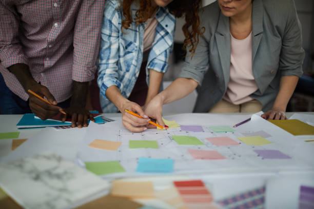 Young Team Planning Business Prooject Closeup of creative business team working on design project focus on table with roadmap and colorful stickie notes, copy space fashion drawing stock pictures, royalty-free photos & images