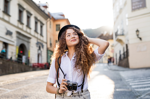 Beautiful young tourist with camera in the old town