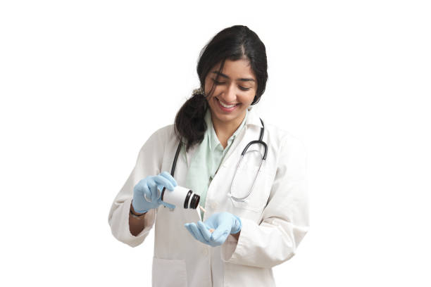Young Venezuelan female doctor smile and take some pills from bottle, isolated. stock photo