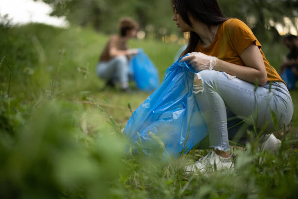 Young volunteers collecting garbage from forest in garbage bags stock photo