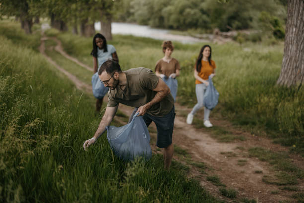 Young volunteers collecting garbage from forest stock photo