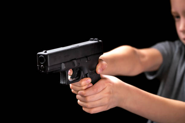 niño caucásico blanco joven sosteniendo y apuntando disparos de pistola - gun violence fotografías e imágenes de stock