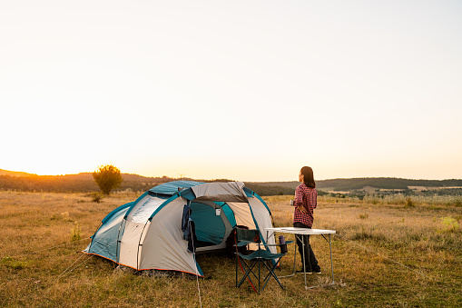 A young woman is admiring and looking at the view during camping in nature.