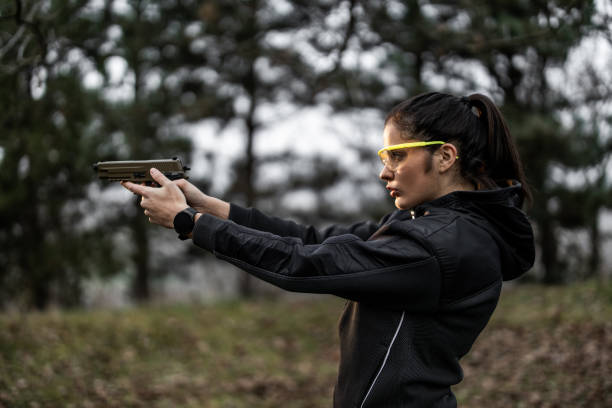 Young woman aiming and practising shooting from pistol at shooting range stock photo
