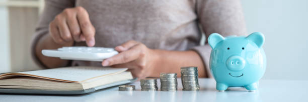 Young woman and piggy bank to planning growing saving strategy with pile coins for future plan fund of travel, education, home and retirement stock photo