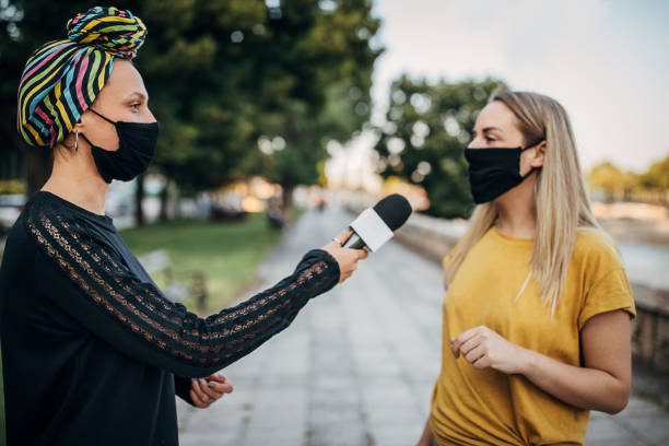junge frau antwortet journalistischen frauen auf der straße während coronavirus pandemie - interview stock-fotos und bilder