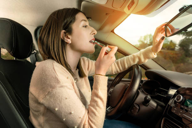 Young woman applying make up in car Young woman applying make up in car important cosmetics stock pictures, royalty-free photos & images