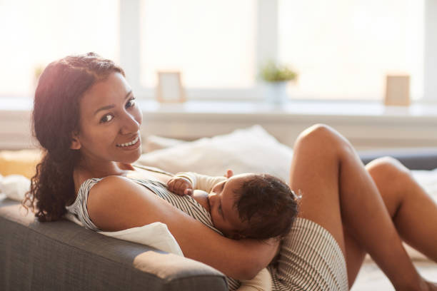 giovane donna che allatta il bambino a casa - allattamento foto e immagini stock