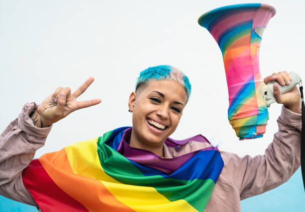 jonge vrouw die homotrotsgebeurtenis viert die regenboogvlagsymbool van lgbt sociale beweging draagt - gay demonstration stockfoto's en -beelden