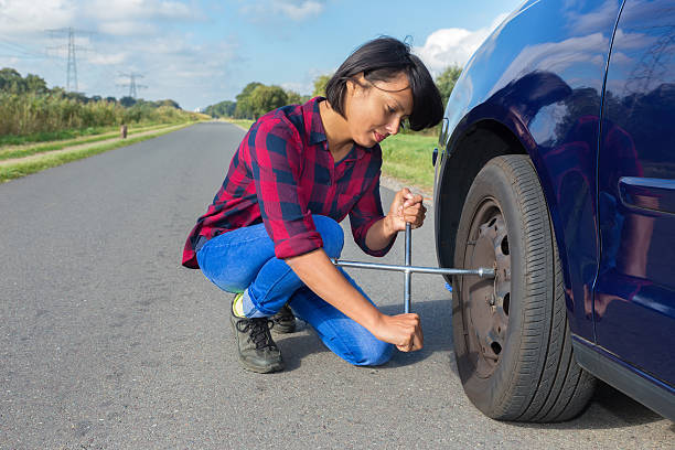Young woman changing car wheel on country road stock photo