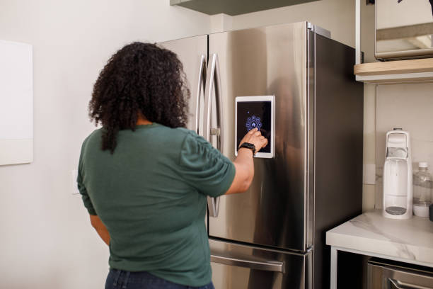 Young woman checking information from smart fridge stock photo