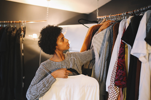 Young mixed race woman in her apartment in downtown Los Angeles is checking out her wardrobe, choosing what to wear today.