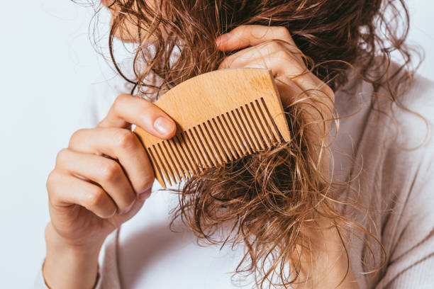 Young woman combing tangled ends of her curly hair stock photo