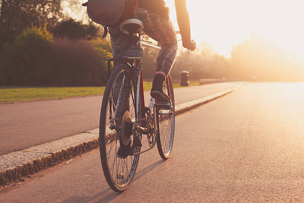 Young woman cycling in the park at sunset stock photo