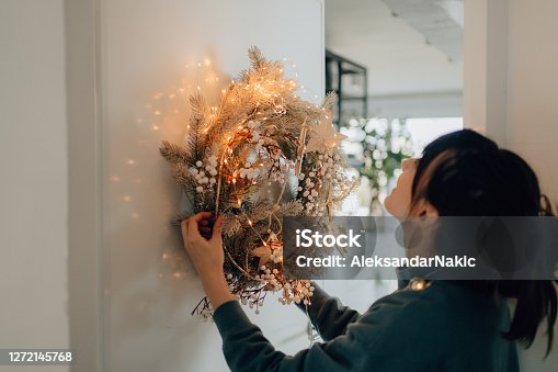 istock Young woman decorating her living room for the upcoming holidays 1272145768