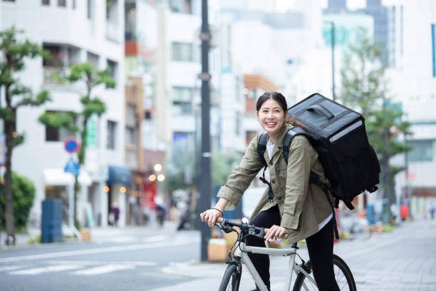 自転車で荷物を配達している若い女性 - 副業 ストックフォトと画像