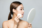 若い女性が化粧をしています。肌ケアのコンセプトです。