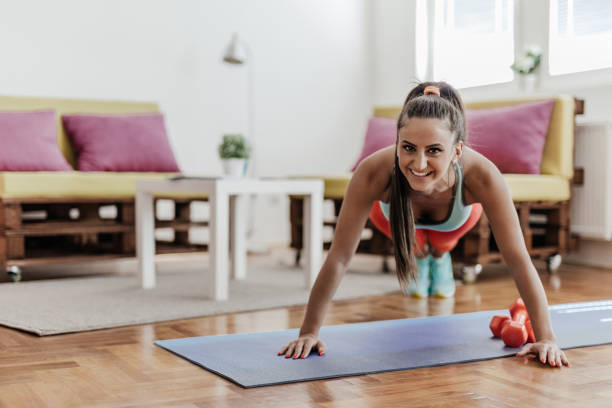 Young woman doing some push ups in her living room Young woman doing push ups chest exercises at home stock pictures, royalty-free photos & images