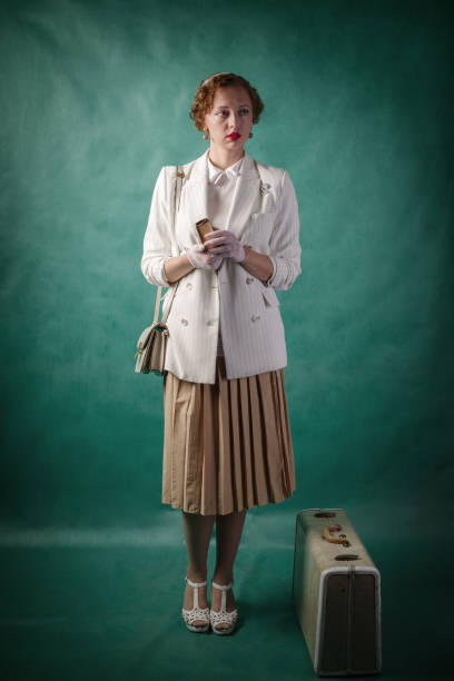 Young woman, dressed in retro style, with a suitcase and a book in her hands stock photo