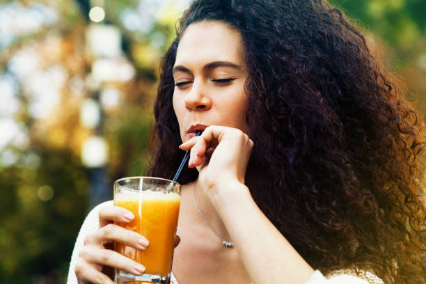 Young woman drinking orange juice stock photo