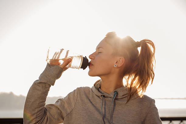 Young woman drinking water after cycling stock photo