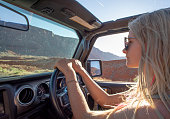 istock Young woman drives off-road vehicle down desert road 1321954480