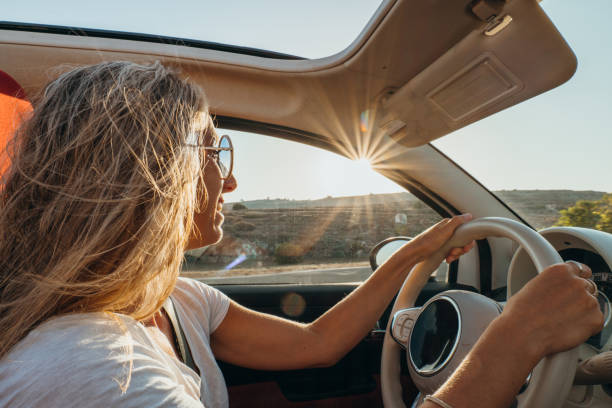 Young woman driving car at sunset, road trip concept stock photo