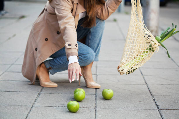 Young woman dropping groceries on sidewalk stock photo