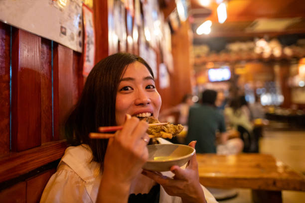 Young woman eating Japanese 'Mozuku Tempura' in Izakaya restaurant Young woman eating Japanese 'Mozuku Tempura' in Izakaya restaurant tourism photos stock pictures, royalty-free photos & images