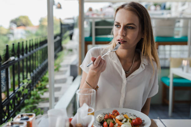 Young woman eating salad in a restaurant during her vacation stock photo