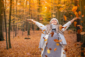 Girl walking in the park in autumn and smiles with open arms